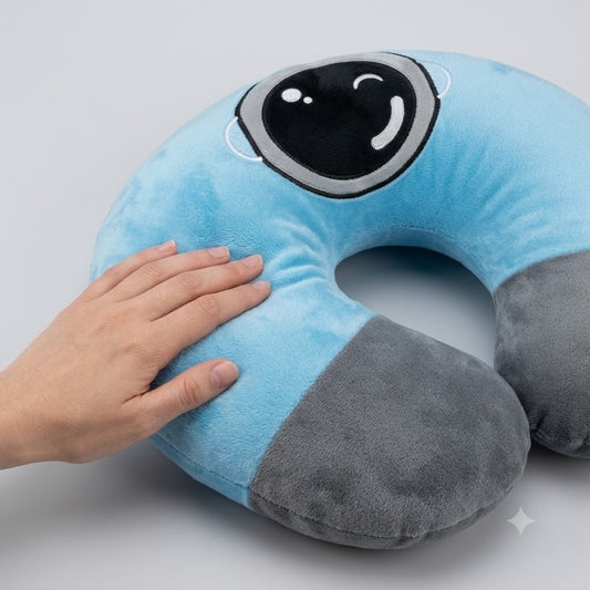 Two-tone light blue and dark grey plush U-shaped travel neck pillow with embroidered winking cartoon face patch